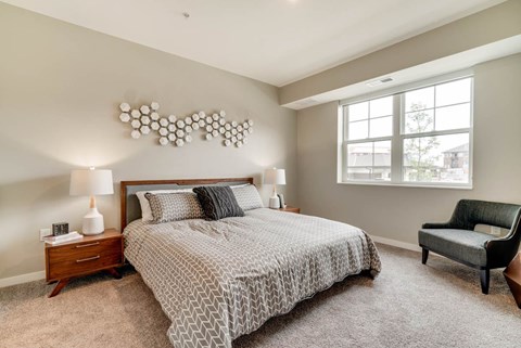A bedroom with a large bed, a chair, and a lamp.