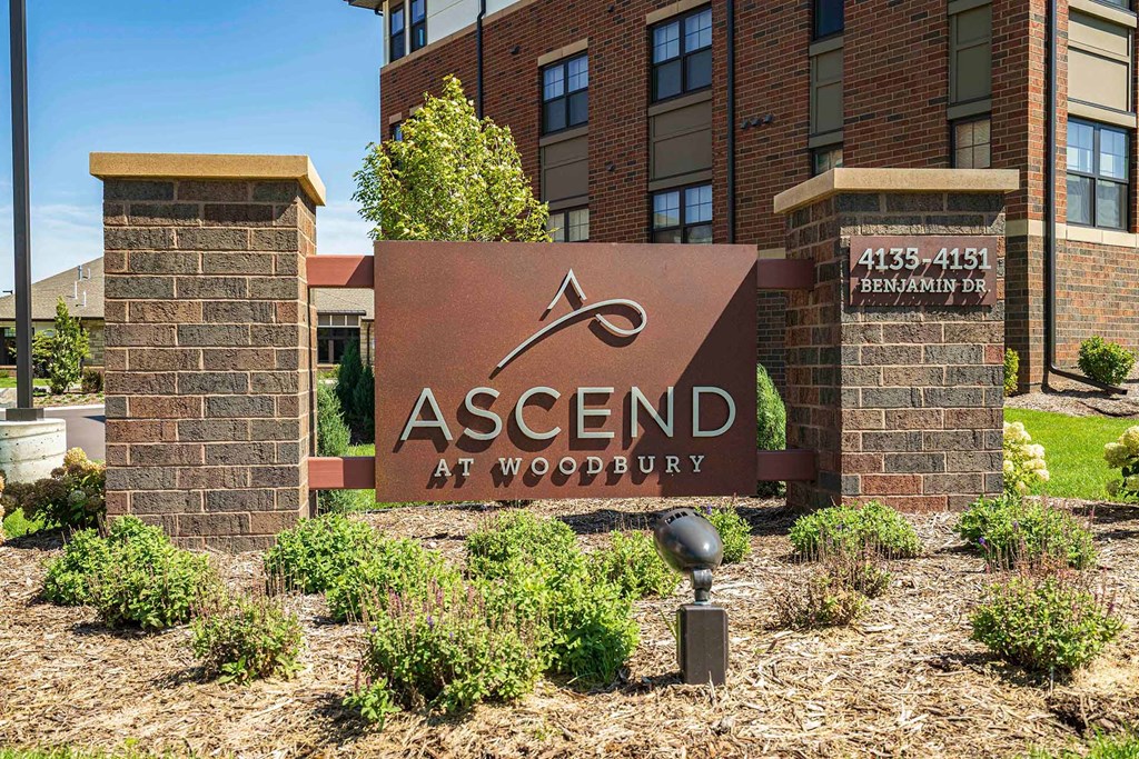outdoor brick sign for Ascend at Woodbury in front of apartment building