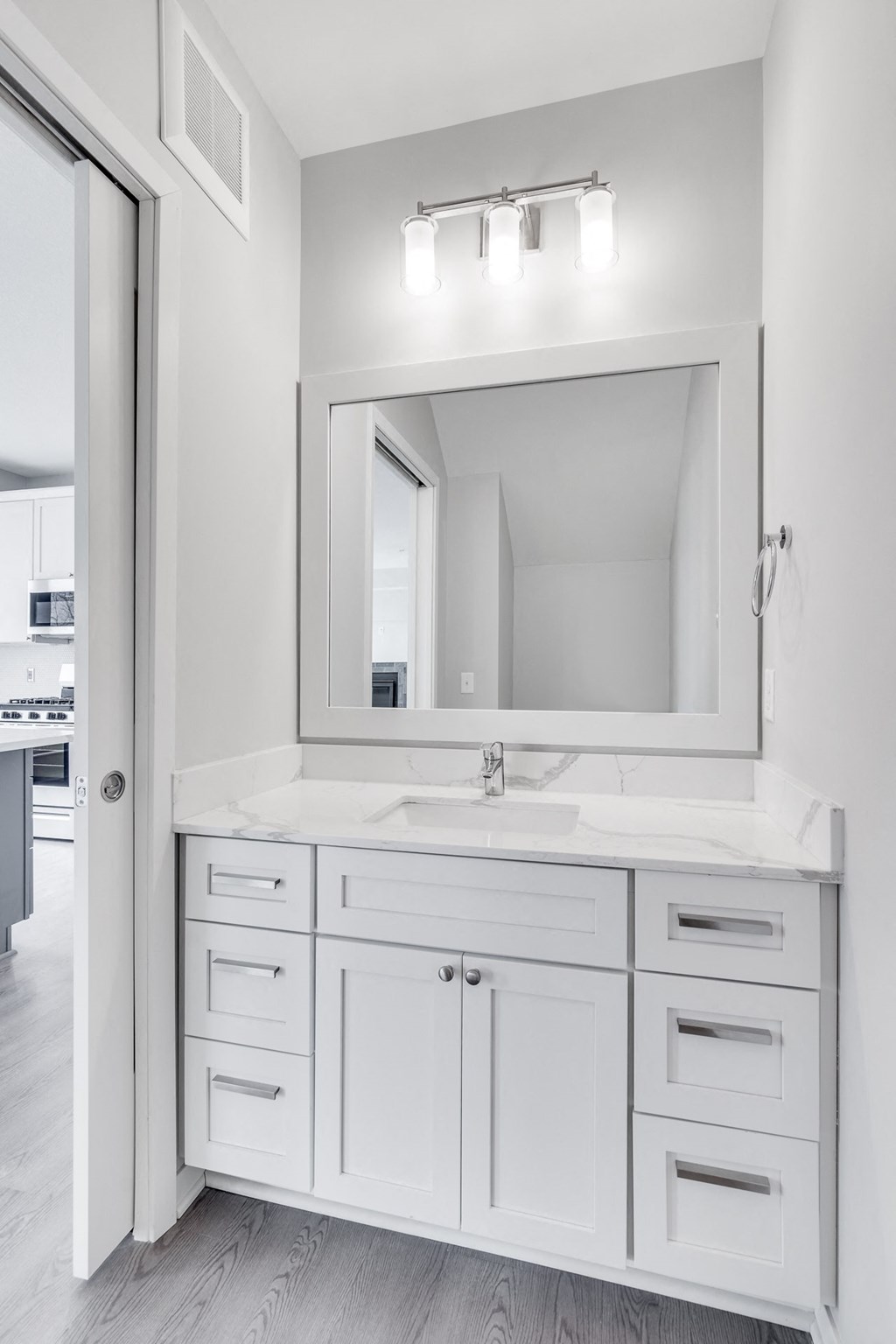Bathroom vanity with light gray finishes and large mirror at Aspire at CityPlace in Woodbury, Minnesota