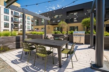 Outdoor lounging and cooking area with grill, table, and chairs at Aspire at Cityplace