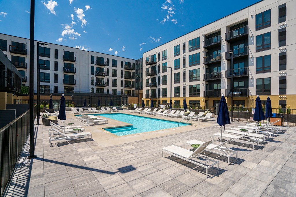 Resort style swimming pool with white sun loungers and green circular side tables at Aspire at CityPlace