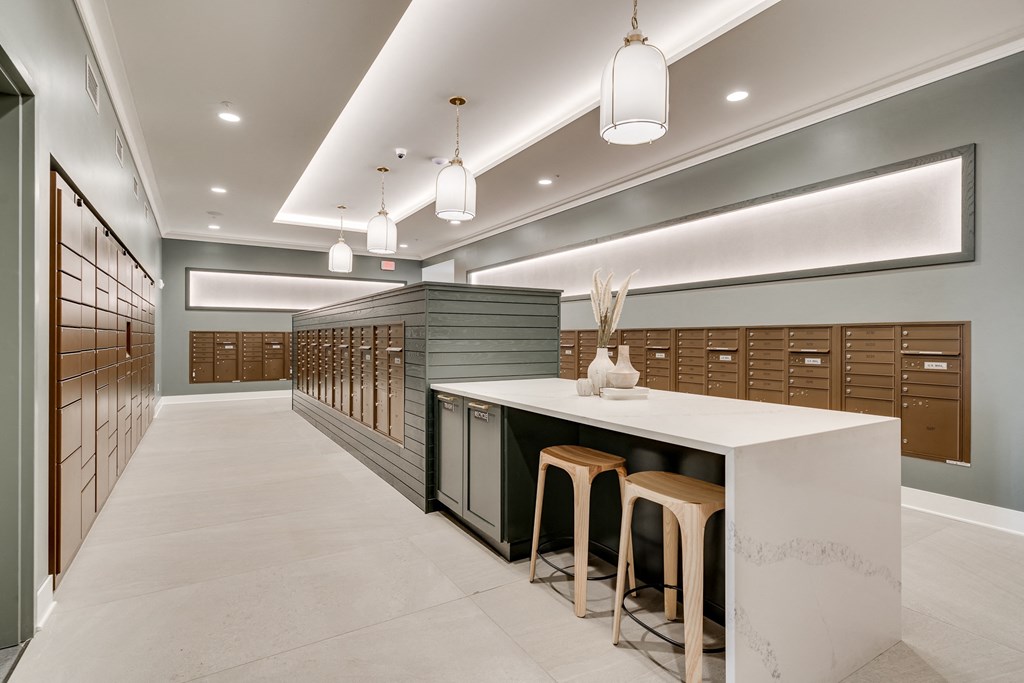 Mailroom lined with package lockers and mailboxes and island seating in the middle