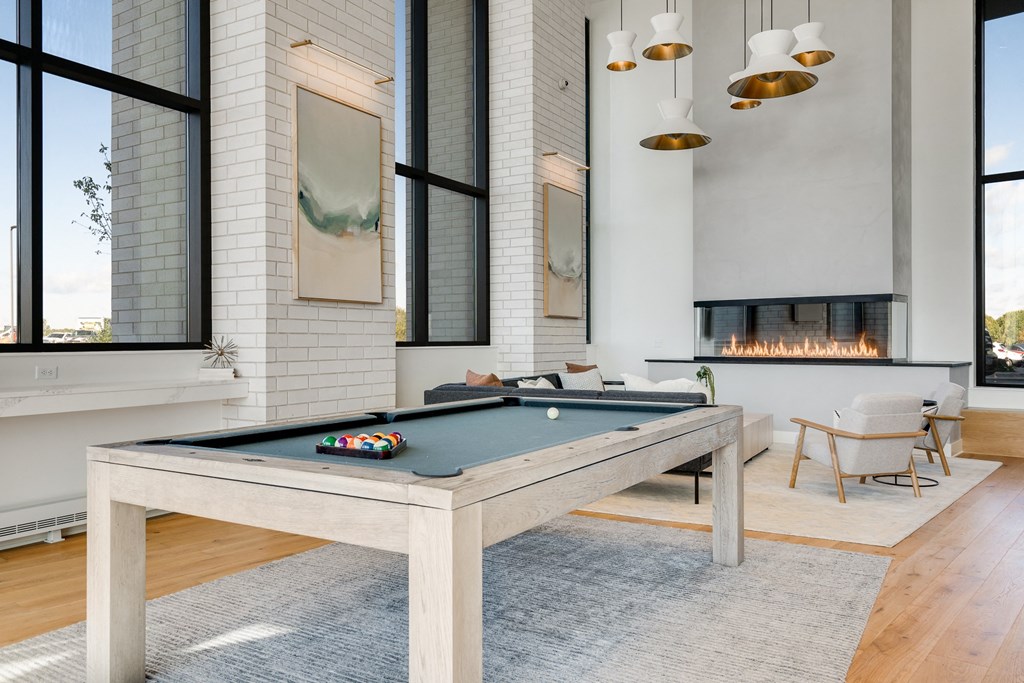 Lobby space with wood pool table and seating area around an electric fireplace