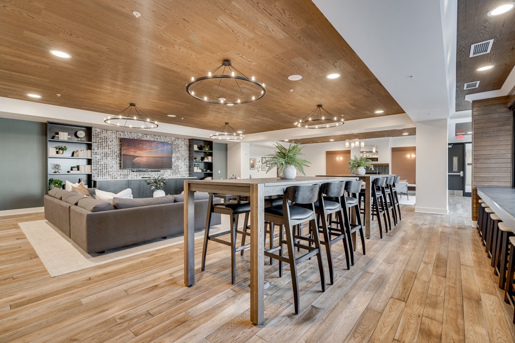 Community room with table seating and large sectionals around a TV at Aspire