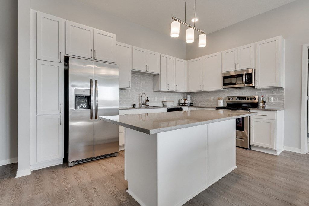 Luxury kitchen with white cabinets and an island at Aspire at CityPlace in Woodbury MN 55125