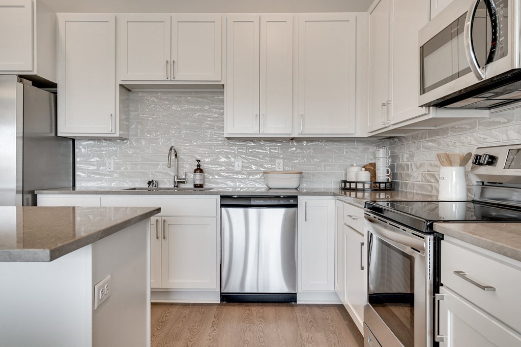 Luxury kitchen with white cabinets and an island at Aspire at CityPlace in Woodbury MN 55125