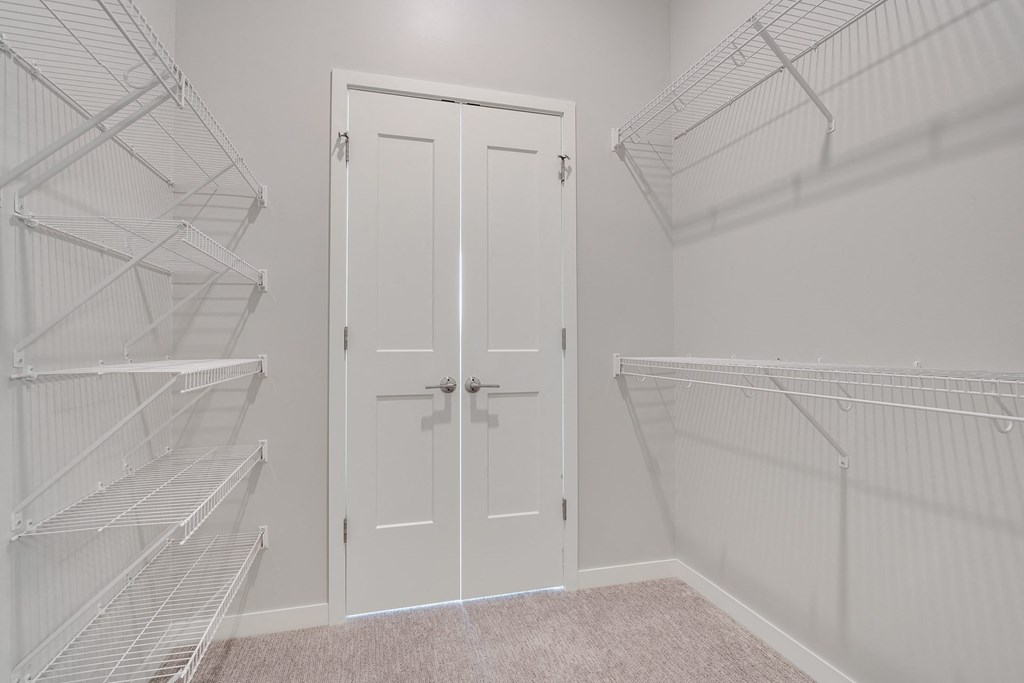 Large walk in closet with double doors and wire shelves on each side in 2 bedroom apartment in Woodbury MN 55125