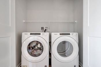 Side by side front loader washer and dryer in a laundry closet in two bedroom luxury apartment Woodbury MN 55125