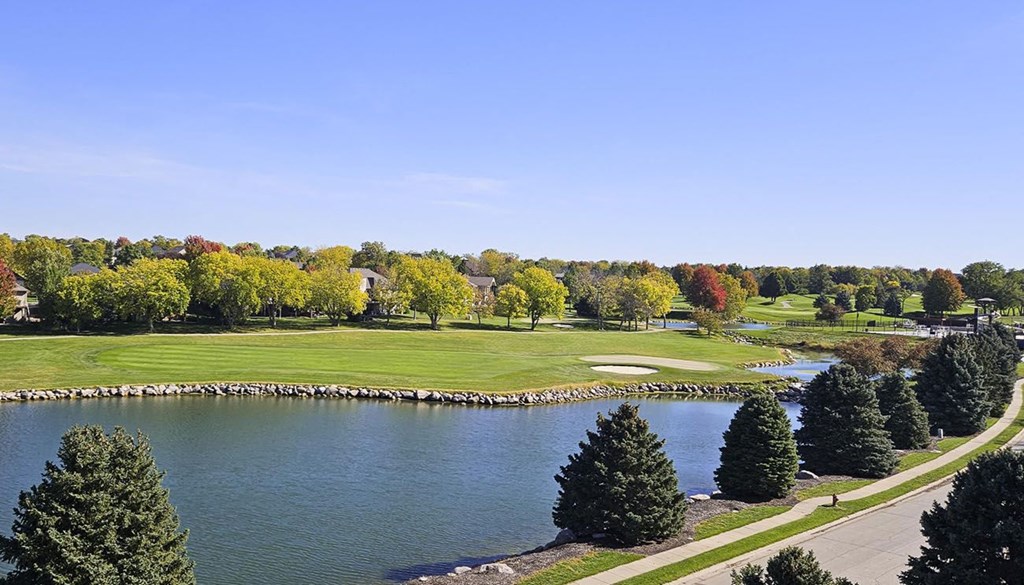 a view of a golf course and a pond surrounded by trees