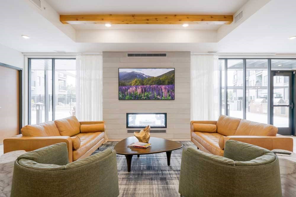 A clubroom with a TV lounge, two-way fireplace, and lounge seating.