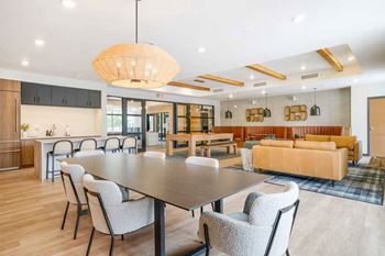 A clubroom with a dining area next to a kitchenette and lounge area that residents can rent out for private events.