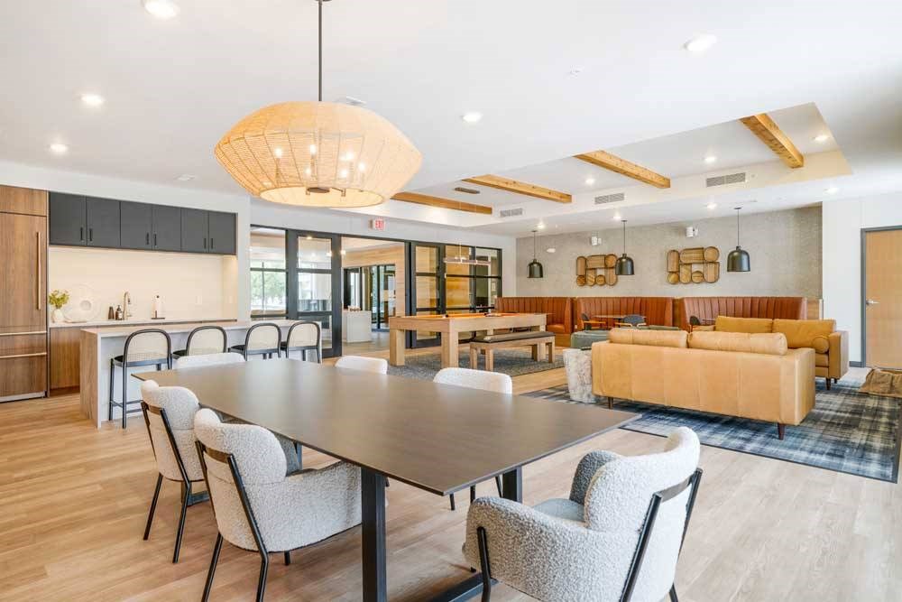 A clubroom with a dining area next to a kitchenette and lounge area that residents can rent out for private events.