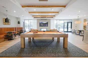 A clubroom with a wooden pool table with orange felt.
