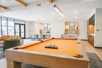 A clubroom with a orange felt pool table.
