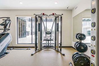 a 24-hour fitness center with a Smith machine and racks of weights