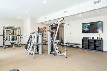 a 24-hour fitness center with several weight machines and a tv