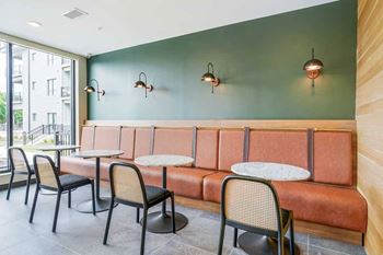 a row of tables, booths, and chairs against a green accent wall and floor to ceiling windows