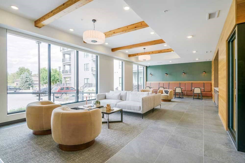 a modern, cafe-style lounge with armchairs, couches, tables and chair, and a coffee bar