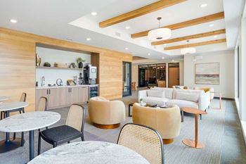 a modern, cafe-style lounge with armchairs, couches, tables and chair, and a coffee bar