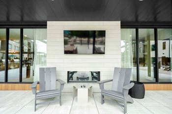 A modern outdoor seating area with a television mounted on the wall.