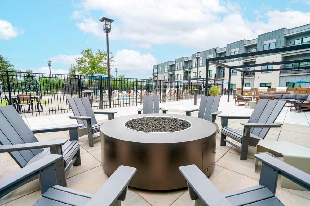 A conversational fire pit with several Adirondack chairs surrounding it.