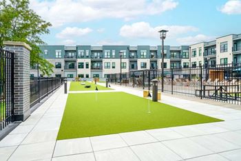 A courtyard with a putting green turf with multiple pins to practice your short game on.