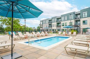 A lounge pool surrounded by several lounge chairs and umbrellas for shade.