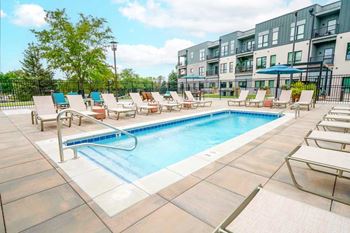A lounge pool surrounded by several lounge chairs and umbrellas for shade.