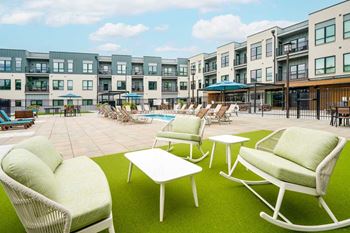 A patio space in the courtyard, with bench seating and rocking chairs on turf.