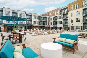 A seating area with cushioned benches and an umbrella covered table next to a lounge pool.