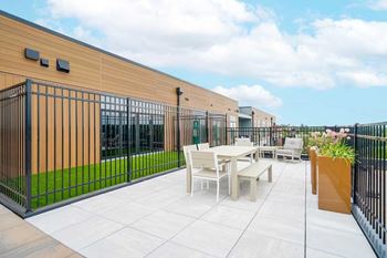 a rooftop patio with a fenced-in dog run, outdoor dining space, and lounge seating