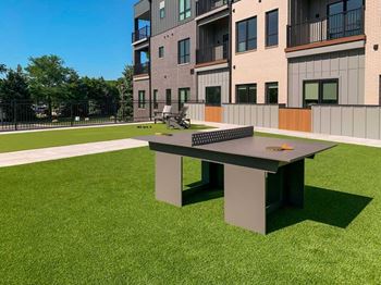 a modern ping pong table in a courtyard with turf grass
