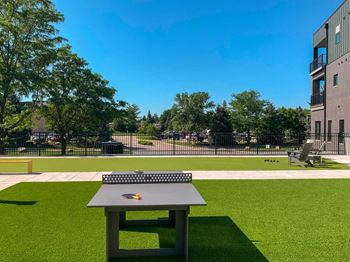 a modern ping pong table in a courtyard with turf grass