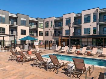a lounge pool with several chaise lounge chairs and umbrellas surrounding it