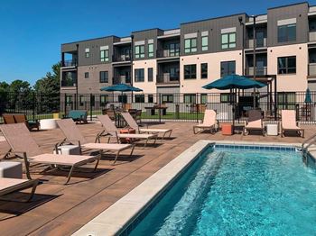 a lounge pool with several chaise lounge chairs and umbrellas surrounding it