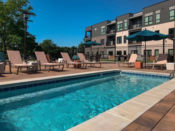 a lounge pool with several chaise lounge chairs and umbrellas surrounding it