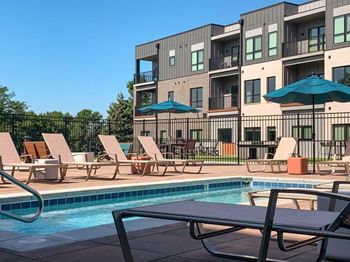 a lounge pool with several chaise lounge chairs and umbrellas surrounding it