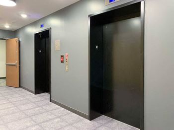 two elevators with black doors in a tiled room