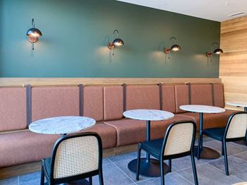 a row of chairs and tables and booth seating in front of a modern green wall
