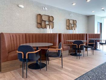 a modern dining/seating area with a brown leather booths and black chairs in the clubroom