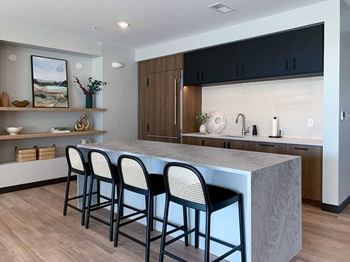 a kitchen with a marble island and black barstools in the clubroom