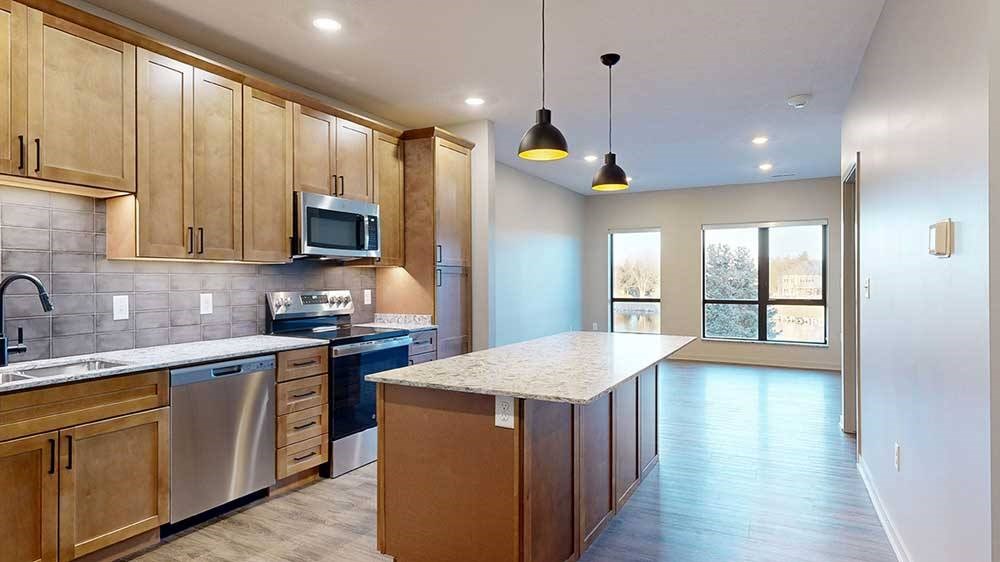 1-Bed Owl (#210) - Kitchen Island a kitchen with a large central island featuring tan wooden cabinets and light quartz countertops