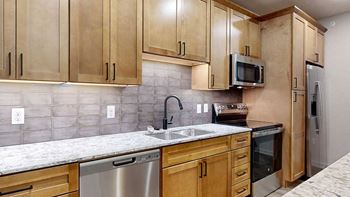 a kitchen with wooden cabinets and a light granite countertop.