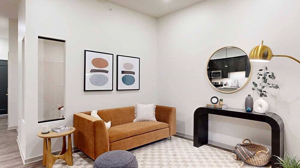 a studio living area with a sofa, chair, and modern art on the wall