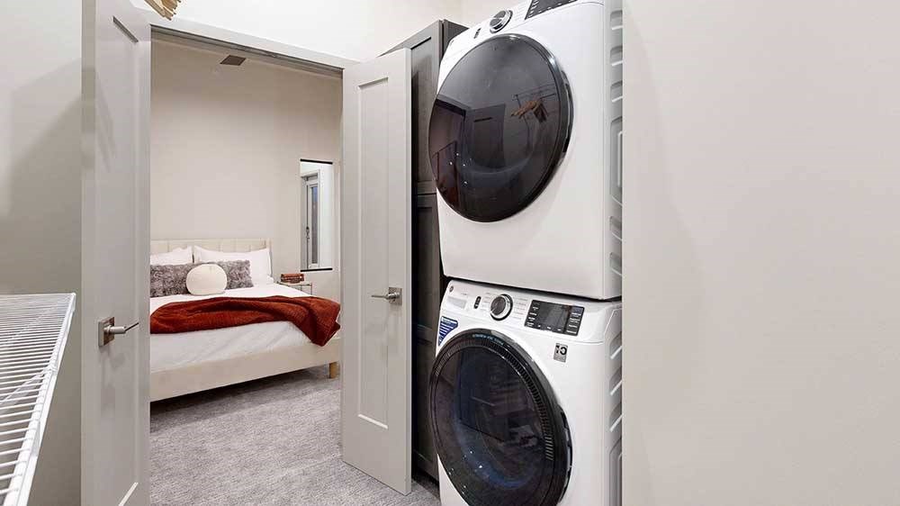 a stacked washer and dryer inside a walk-in closet