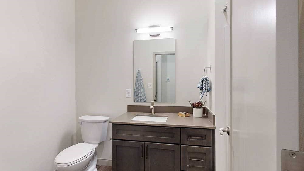 a bathroom with a quartz vanity sink and a mirror with overhead lighting