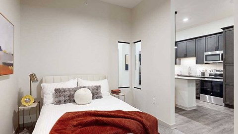 a bed with a red throw blanket and neutral-toned walls