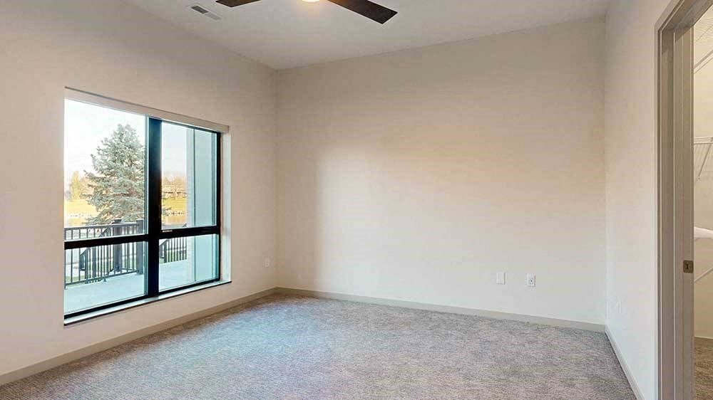a bedroom with a large window and a ceiling fan