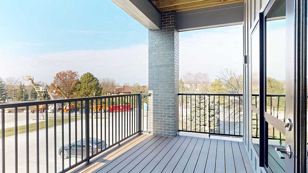 a balcony with a black metal railing and a brick pillar