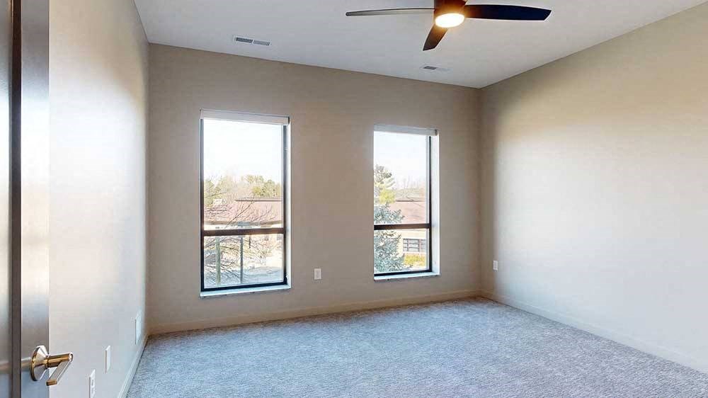 a bedroom with a carpeted floor and two windows